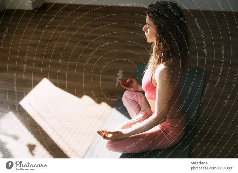 A young girl with her eyes closed meditates in the lotus position in the classroom.Sports, fitness, yoga. Side view, space for text woman meditating exercise