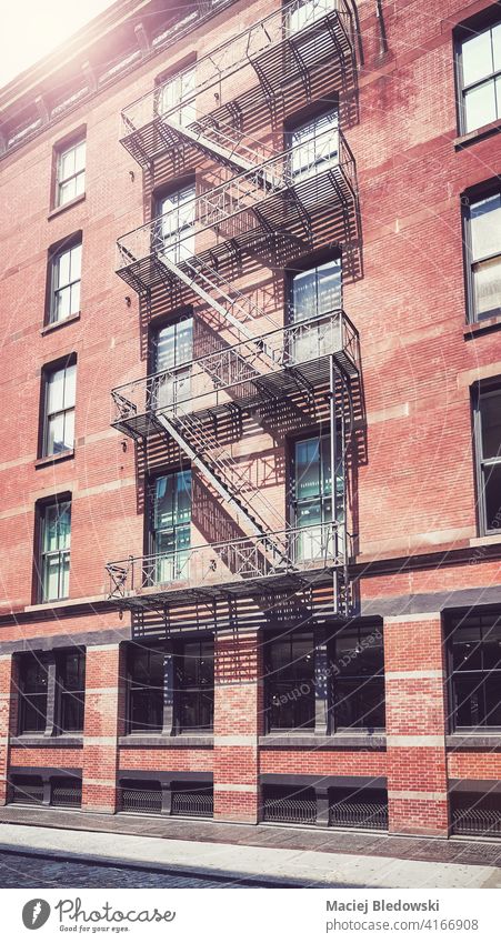 Old brick building with iron fire escape, color toning applied, New York City, USA. city Manhattan old house street apartment architecture stairs cityscape