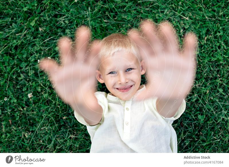 Happy boy resting on lawn in daylight kid happy child grass chill weekend pleasure hand behind head relax cheerful blond childhood carefree summer delight