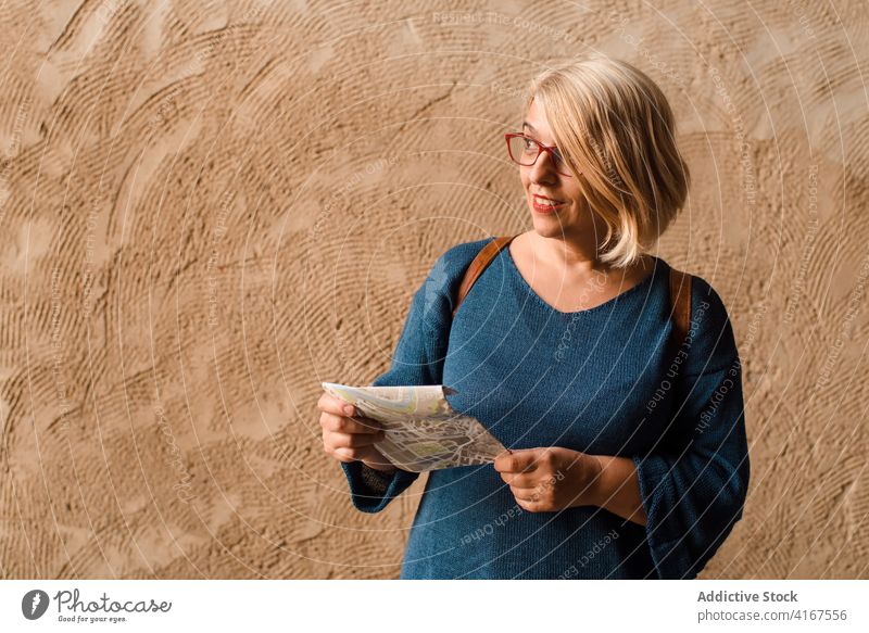 Curious female traveler with map standing near old wall woman street historic explore curious navigate town route check cuenca spain excursion smile read