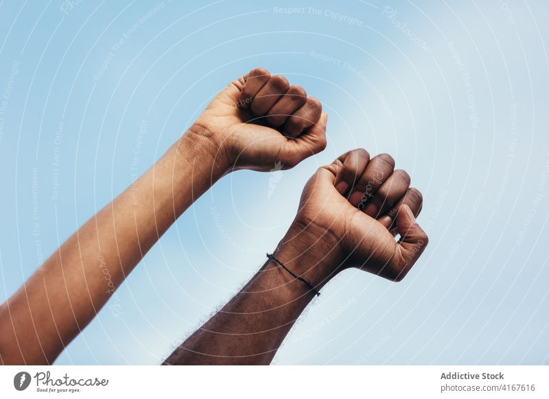 Fists of black people against a blue sky man detail male fist hand person human power isolated background gesture finger arm fight aggressive strong closeup