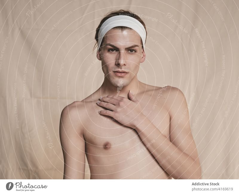 Sensual androgynous male model touching neck man sensual touch neck shirtless slim transgender allure tender appearance young queer lgbtq headband style trendy