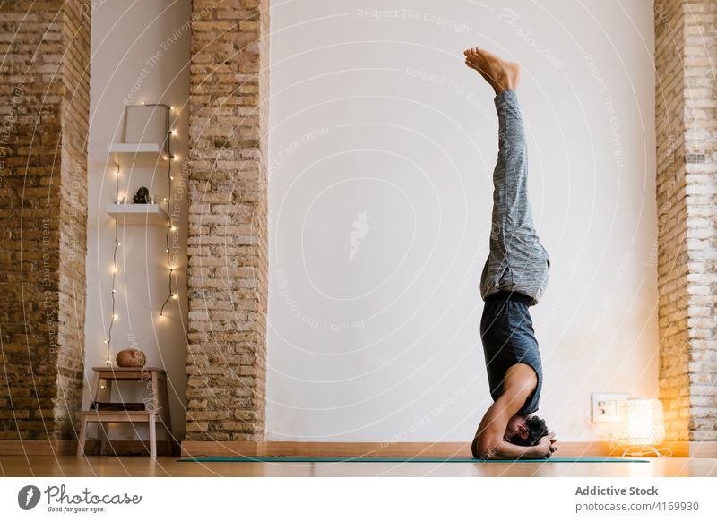 Anonymous guy doing Headstand in studio man headstand yoga lesson practice upside down balance cozy healthy male adult barefoot zen asana serene calm peaceful