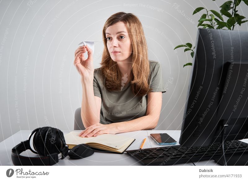 Woman hold paper plane while working at home office procrastinate freelance online woman lazy business workspace computer organization creative planning