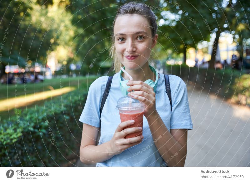 Happy female with drink standing in park summer happy girl blonde teen beverage lifestyle woman joy young enjoy delight communicate positive carefree vacation