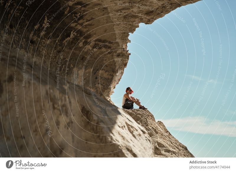 Traveling woman sitting on rock in highlands hiker mountain trekking viewpoint relax freedom enjoy hill female rocky adventure majestic scenery tourism summer