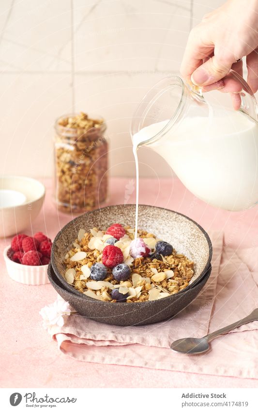 Breakfast with granola, berries and milk breakfast food healthy hand pouring organic cereal fruit muesli berry bowl grain diet flake snack yogurt fresh natural