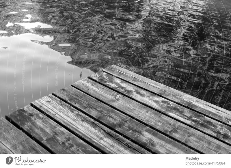 Old wooden footbridge for bathers in summer at the Mittersee in Füssen in the Ostallgäu in the Free State of Bavaria, photographed in classic black and white