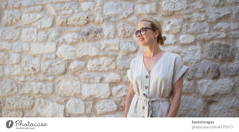 A woman wearing sunglasses standing in front of a wall photo