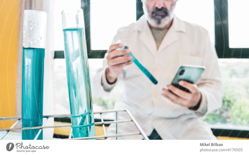 Test tubes with liquid and scientist with lab coat and a mobile phone in a scientific laboratory.  Science concept. science testing biotechnology expertise