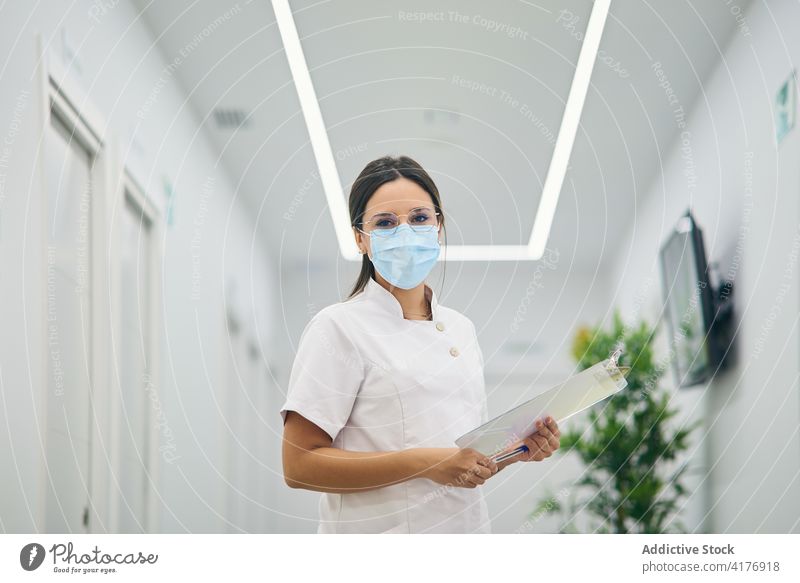 Cosmetologist in uniform in beauty clinic beautician cosmetology woman cosmetician dermatology specialist mask hallway female medical clipboard modern