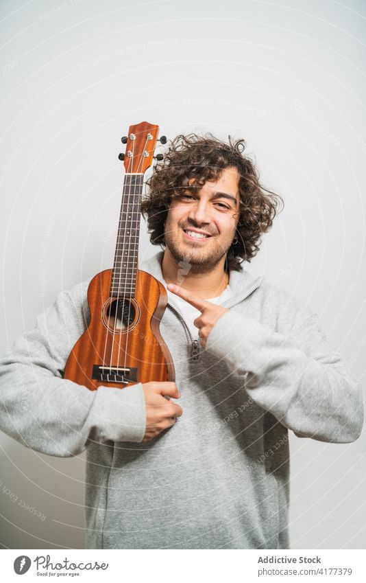 Cheerful man playing ukulele guitar cheerful musician perform positive instrument happy young ethnic hispanic male melody lifestyle song sound acoustic