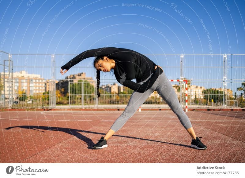 Focused sportswoman stretching during workout calisthenics training flexible warm up sports ground exercise female athlete wellness healthy fitness vitality