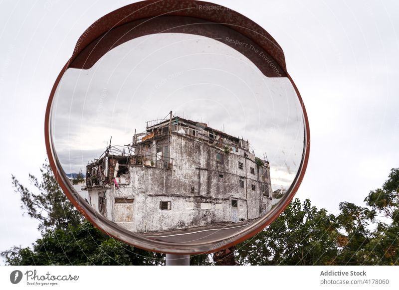 Traffic safety mirror with reflection of old building convex traffic road abandoned weathered east coast smooth surface round circular shape security town city