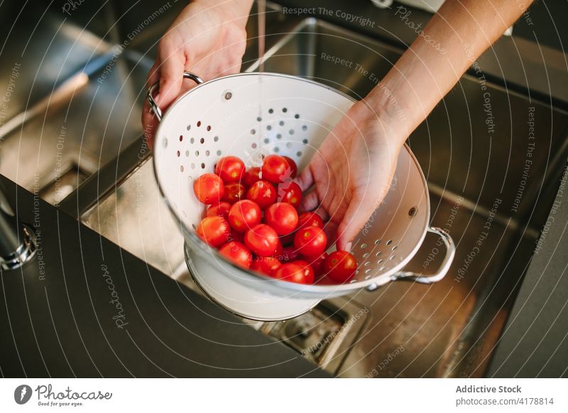 Woman washing fresh tomatoes in strainer cherry woman vegetable pile water clean kitchen female ripe metal organic ingredient natural vitamin healthy colander