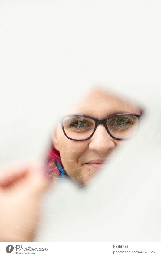 Woman looks friendly through a mirror shard into the camera Mirror Feminine Young woman Human being Adults 18 - 30 years portrait Face Head reflection