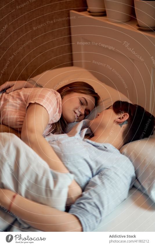 Couple of women lying in bed in morning couple lesbian sleep together blanket lgbt girlfriend affection bedroom bonding relax home relationship cuddle love