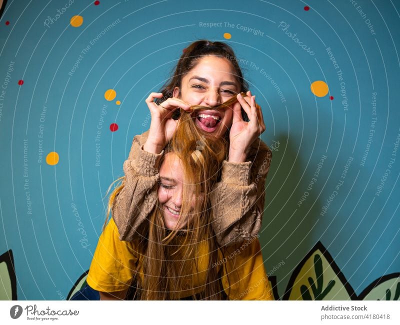 Cheerful woman showing tongue with having piggyback ride on friend women best friend fun laugh friendship joy grimace tongue out together female having fun glad