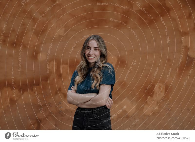 Smiling woman with crossed arms on brown background in city arms crossed smile feminine sincere friendly shy gentle street lifestyle town tender romantic timid