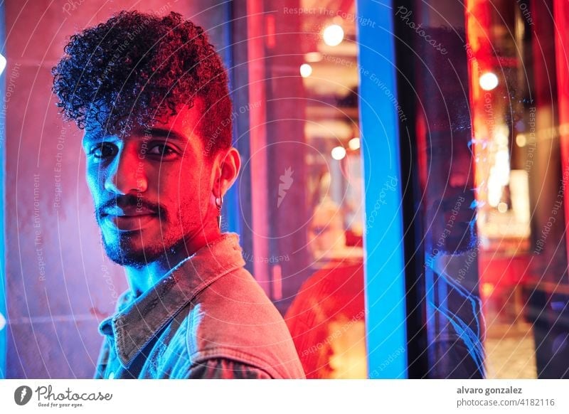 young hispanic man close to a neon light with blue and red lights male model adult people person portrait guy face handsome caucasian attractive background
