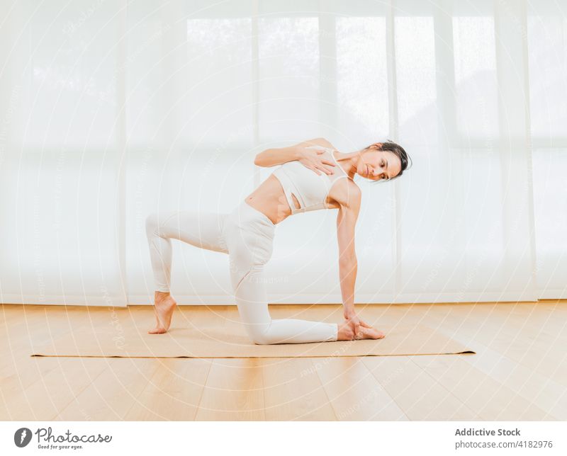 Smiling woman stretching body in twisting yoga position - a