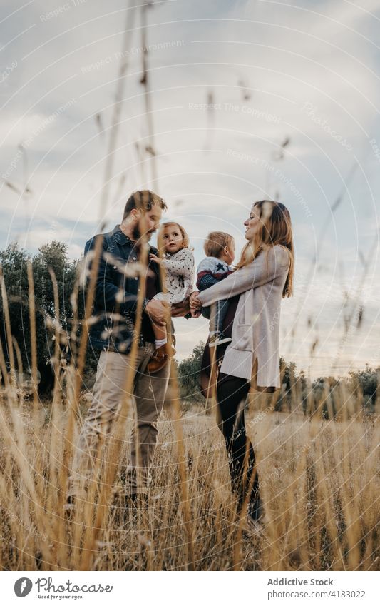 Positive family having fun in countryside play children couple together playful little weekend relationship kid love happy cheerful father fondness smile parent