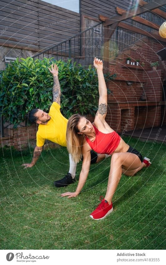 Athletic man and woman doing yoga in Revolved Crescent Lunge on the Knee pose sportswoman sportsman practice flexible stretch warm up training backyard balance