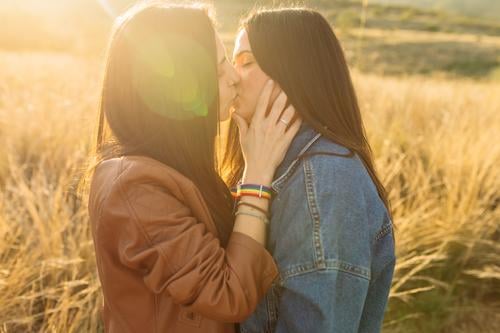 Couple of women kissing in field lesbian couple tender love together relationship lgbt lgbtq homosexual enjoy in love affection girlfriend eyes closed bonding