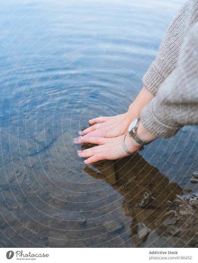 Anonymous tourist touching pure lake water from shore traveler reflection nature vacation mirror trip woman style journey vegetate bright coast weekend female