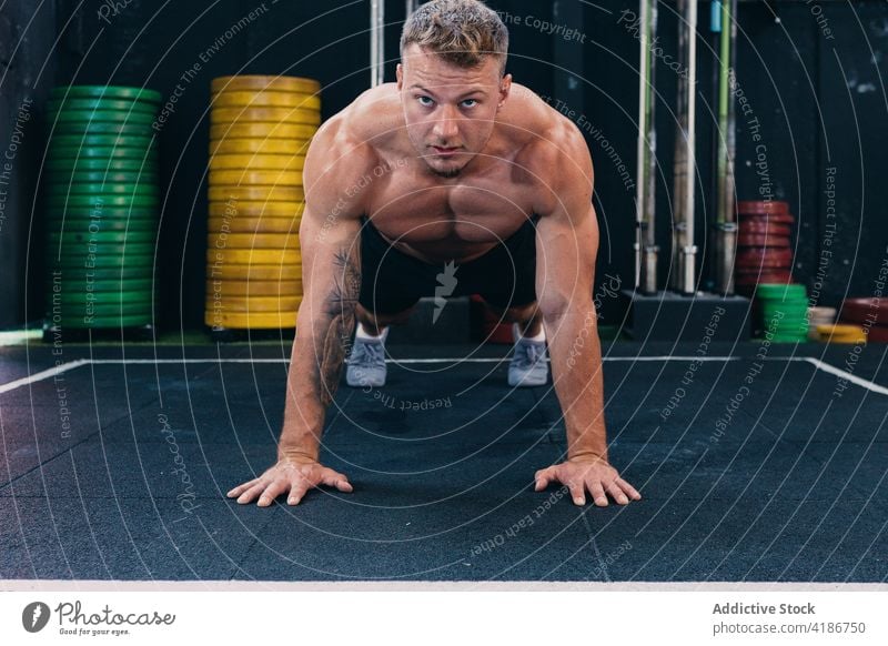 Confident sportsman doing push ups during training in gym exercise workout functional muscular strong determine male naked torso shirtless effort fitness