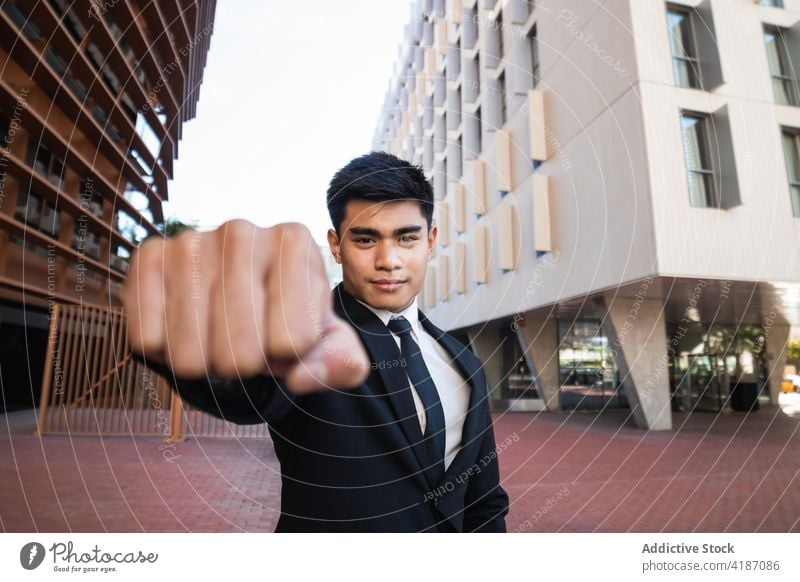 Confident ethnic businessman showing clenched fist confident clench fist determine entrepreneur downtown success concept elegant suit male asian executive