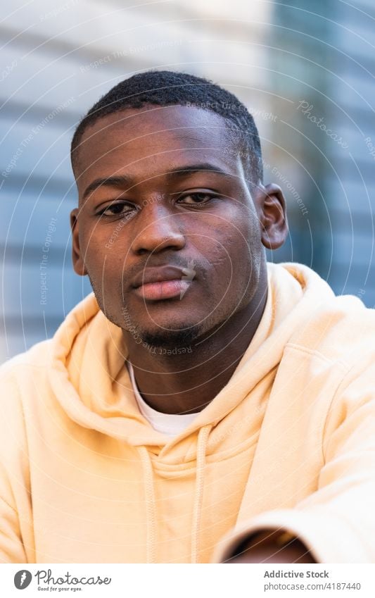 Serious black man in hoodie on street portrait personality serious appearance individuality human face gaze confident stare male brown eyes peaceful look