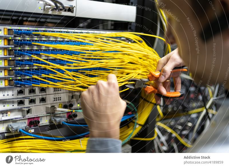 Professional system administrator cutting wires in server man engineer wire cutters connection electronic software facility male control repair technician