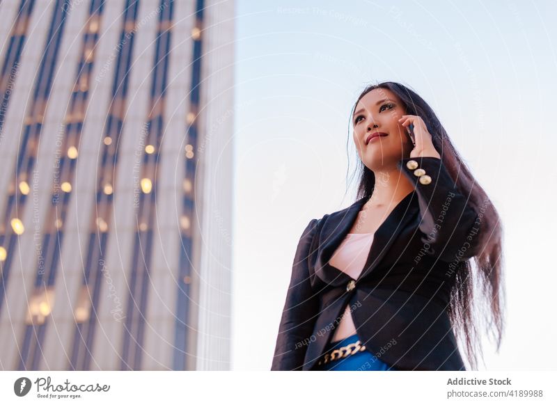 Ethnic businesswoman speaking on smartphone in downtown talk entrepreneur center city using street female asian ethnic style smart casual modern urban