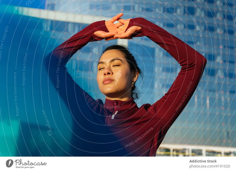 Young woman in sporty outfit standing near city building active style urban sportswear workout fitness confident young ethnic female athlete modern lifestyle