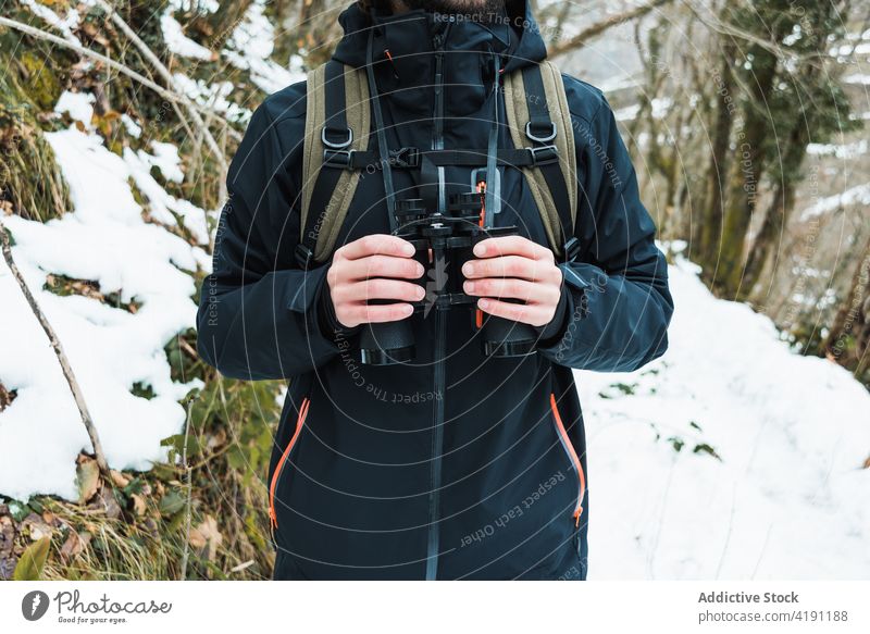 Anonymous traveling man with binoculars in winter forest traveler adventure hiker explore warm clothes male season snow nature woods vacation tourism cold frost