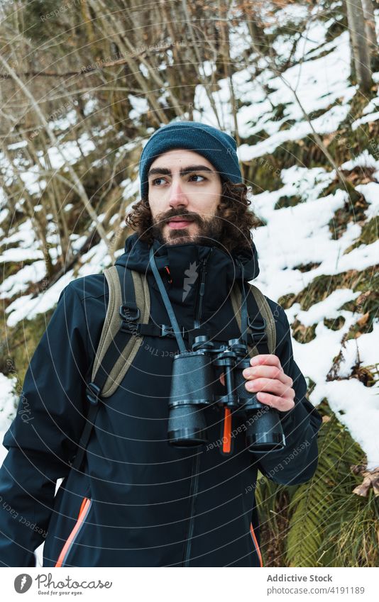 Traveling man with binoculars in winter forest traveler adventure hiker explore warm clothes male season snow nature woods vacation tourism handsome cold frost