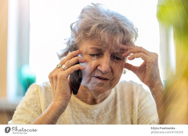 Shot of a tired senior woman using a mobile phone real people candid genuine mature female Caucasian elderly home house old aging domestic life grandmother