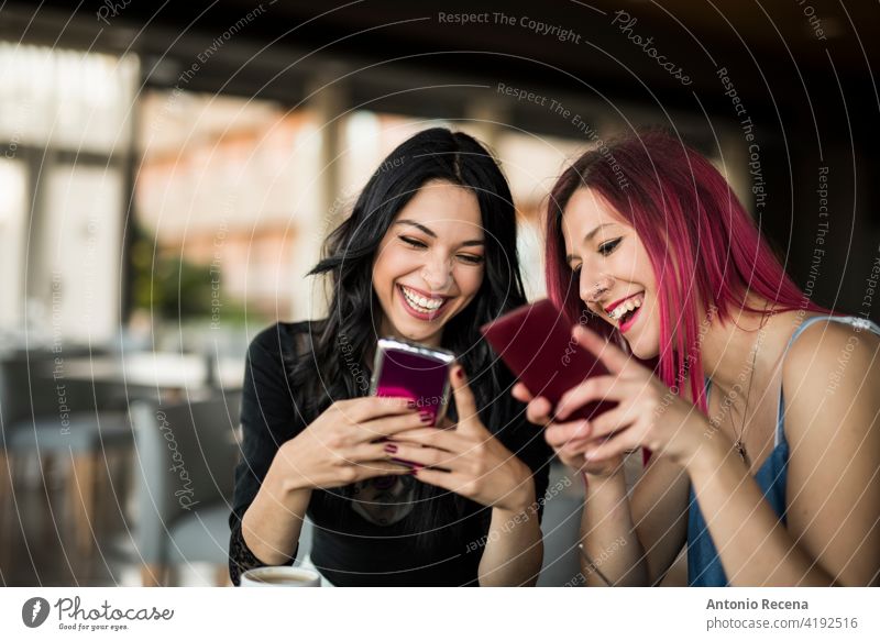 two pretty women looking phones in bar while drinking coke and coffee woman young attractive 20s joy people person youth urban communication tablet technology