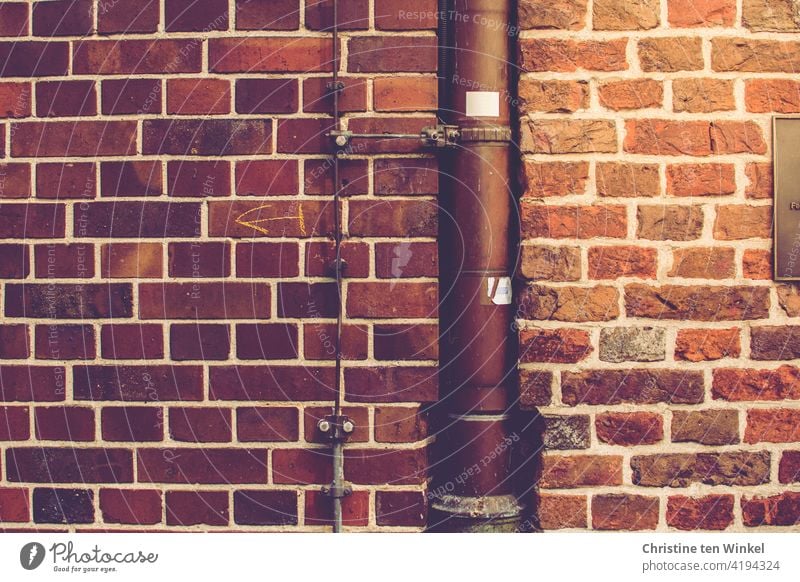 A downpipe and a lightning conductor in the wall at the transition between two brick walls on an old building Downspout Brick wall Wall (barrier) Old Facade