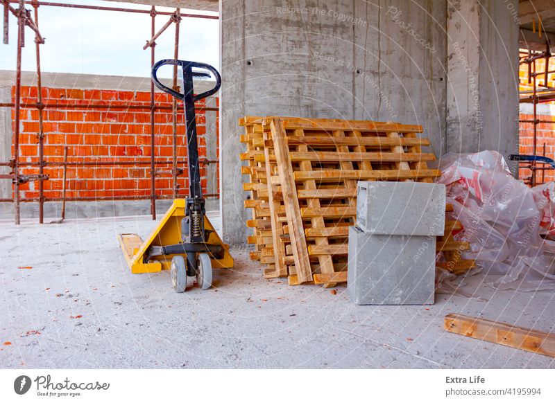 Pedestrian stacker and piled wooden pallets placed against the wall in background Against Architecture Arranged Block Building Site Bunch Cargo Carry Cement