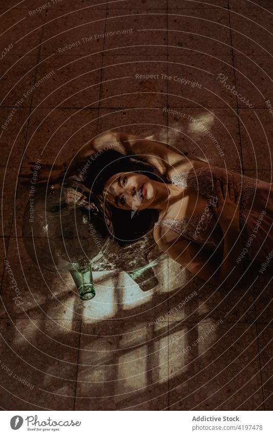 Delicate woman in dress lying on floor serene sunlight feminine delicate tender glare peaceful female room flare idyllic gentle dream harmony glass bottle