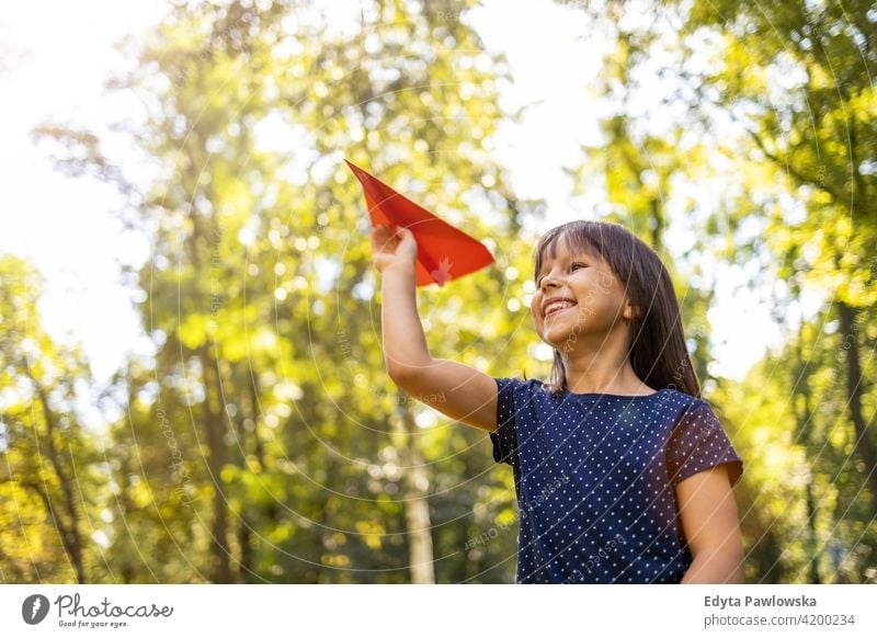 Little girl playing with paper plane in park people child little girl kids childhood outdoors casual cute beautiful portrait lifestyle elementary leisure