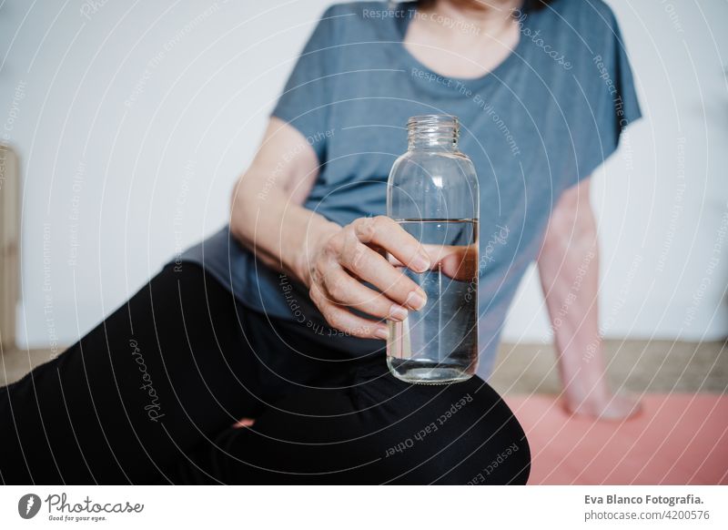 close up view of mature caucasian senior woman practicing yoga pose at home. Holding bottle of water. Healthy lifestyle drinking sport healthy floor active