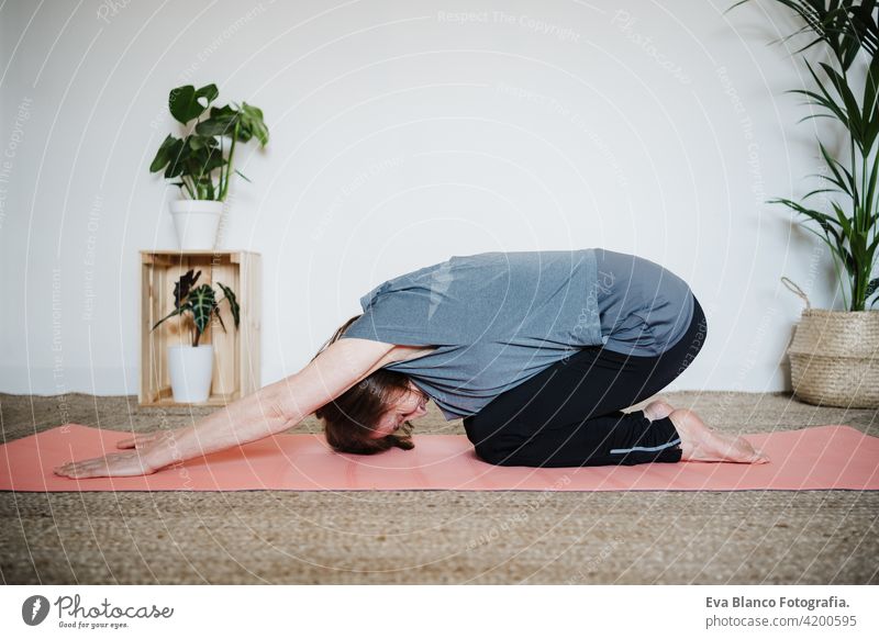top view of mature caucasian senior woman practicing yoga at home on yoga mat. Healthy lifestyle sport healthy floor old active pensioner gym elderly female