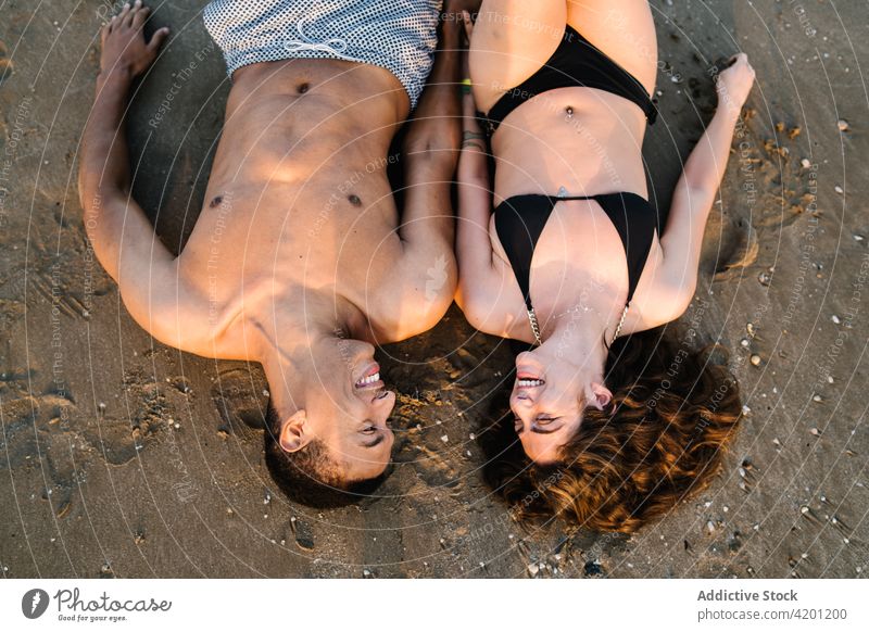 Happy multiethnic couple resting on sandy shore during trip coast relationship love honeymoon romantic enjoy vacation boyfriend girlfriend sincere travel