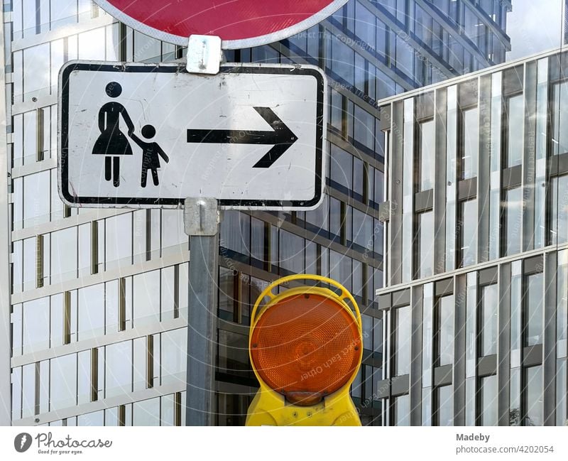 Traffic sign with information for pedestrians and yellow warning light in front of a construction fence at the Senckenberganlage in the Westend of Frankfurt am Main in Hesse