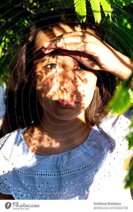 Play of light and shadow portrait of a beautiful tanned caucasian cute girl in the tropical greenery. Travel, vacation, warm countries. female nature summer