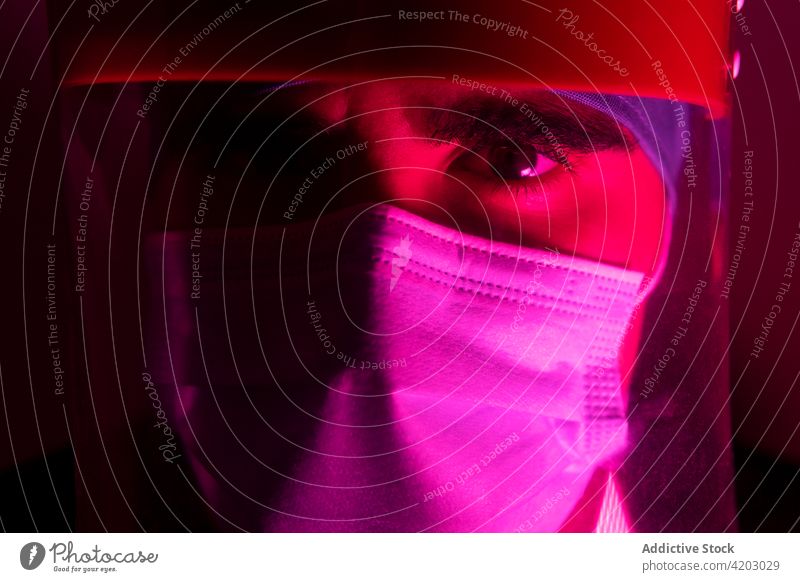 Male doctor in mask in dark room with red neon light surgeon man medical medicine protect illuminate sterile hospital treat clinic serious frown focus