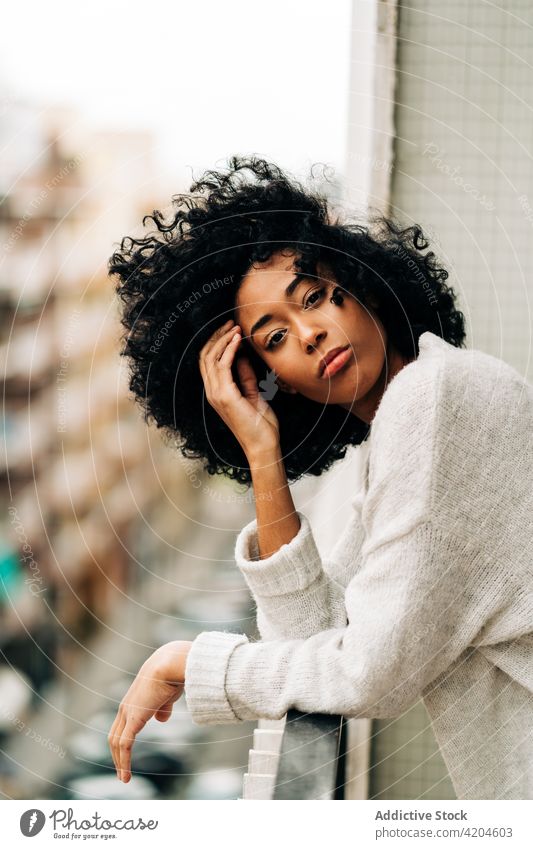 Serene black woman standing on balcony serene terrace dreamy tranquil afro appearance hairstyle peaceful female ethnic african american lean railing daydream